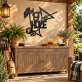 Metallic Black 19th Hole metal wall art on an outdoor golf-themed patio with teak drinks cabinet and plants