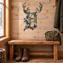 Camouflage Old English D Metal Wall Art with integrated antlers, approximately24inches tall, displayed in a rustic indoor cabin entry.