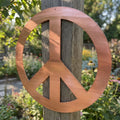 Detailed close-up of the Peace Symbol Metal Wall Art showcasing textured steel surface, craftsmanship, and outdoor garden setting.