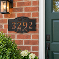 Custom address metal sign with EATON, 3292 and EST 1974 cutouts in black hammertone paint, mounted beside a house front door.