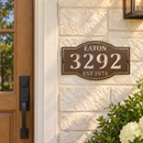 Custom address metal sign with EATON, 3292 and EST 1974 cutouts in brown hammertone paint, mounted beside a house front door.
