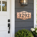 Custom address metal sign with EATON, 3292 and EST 1974 cutouts in copper hammertone paint, mounted beside a house front door.