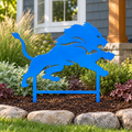 Detroit Lions metal yard art in Honolulu Blue planted in a landscaped garden with stone edging and buried stakes.