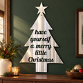 Merry Little Christmas metal wall art in polished silver metal with directional grinding marks on a green entryway wall above a walnut console.