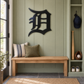 Old English D Metal Wall Art in Black, displayed in an indoor baseball fan setting.
