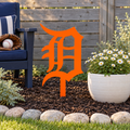 Old English D Metal Yard Art in Orange with a buried center stake, displayed in a backyard baseball-fan garden.