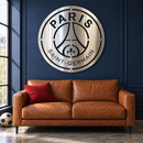 Paris Saint Germain polished metal logo wall art above a cognac leather loveseat.
