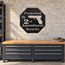 Protected By 2nd Amendment Metal Wall Art Sign in Black, displayed on a light brick wall above a workshop garage workbench.