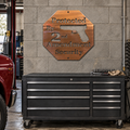 Protected By 2nd Amendment Metal Wall Art Sign in Copper Bronze with directional grinding, mounted on a weathered warm-gray concrete wall above a mechanic's tool cabinet.