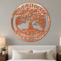 Tree of Life Monogram metal wall art in bright copper above an ivory upholstered bed on a warm grey wall.
