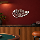 Winged Wheel Metal Wall Art in Polished Metal, displayed in an indoor hockey fan setting.