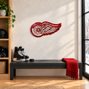 Winged Wheel Metal Wall Art in Red, displayed in an indoor hockey fan setting.